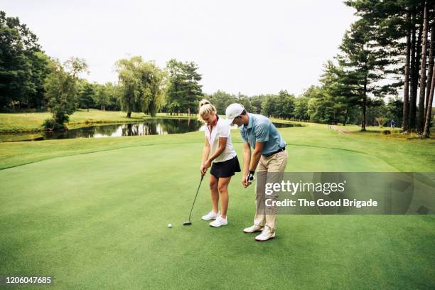 young woman learning how to play golf - golftraining stock-fotos und bilder