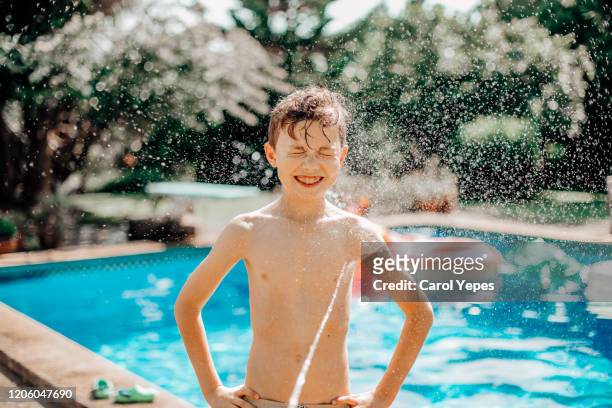 boy splashing at poolside in summer - bath shower stock pictures, royalty-free photos & images