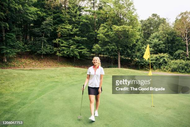 portrait of smiling woman standing on putting green - women golf stock pictures, royalty-free photos & images