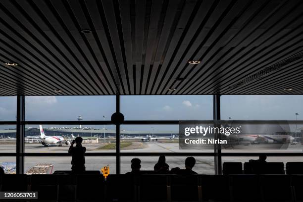 silhouettes of passengers waiting for their flight - changi stock pictures, royalty-free photos & images