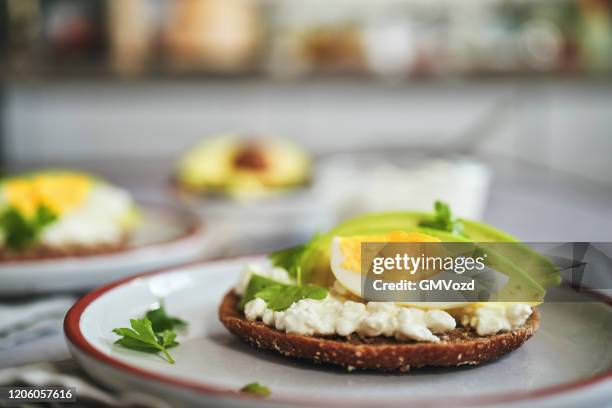 zubereitung von avocado sandwich mit braunbrot, hüttenkäse und eiern - hüttenkäse stock-fotos und bilder