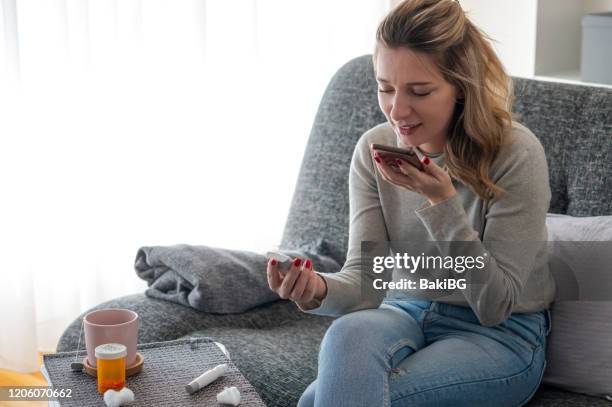 young woman checking glucose level  and video chatting with her doctor at home - video reviewed stock pictures, royalty-free photos & images