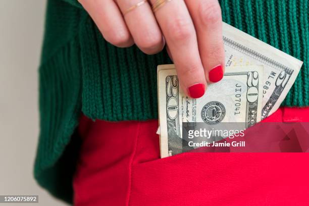 woman putting money in pocket - pocket stock pictures, royalty-free photos & images