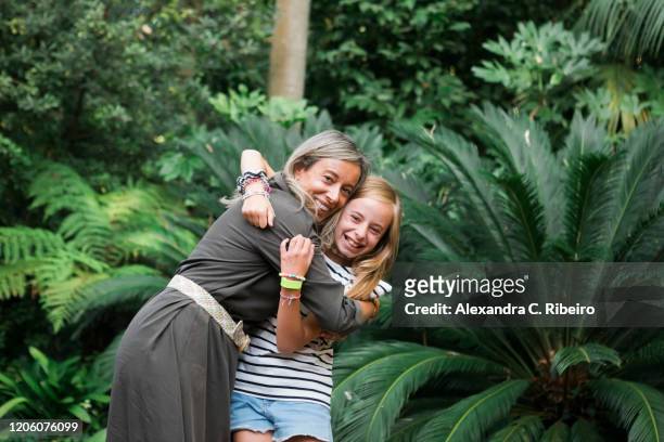 mother and daughter smiling and embracing by bush - alexandra mora bildbanksfoton och bilder