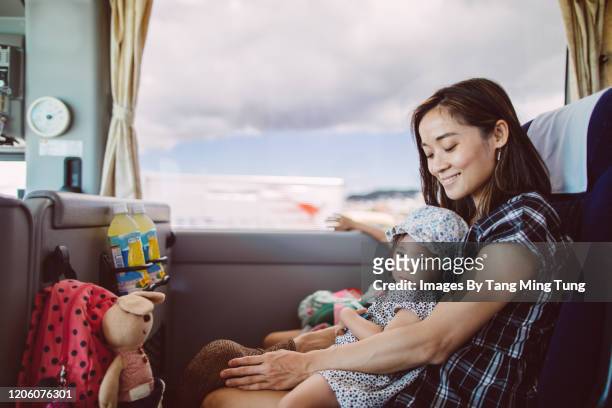 pretty young mom riding on a coach joyfully with her lovely little daughter during traveling trip. - coach bus photos et images de collection
