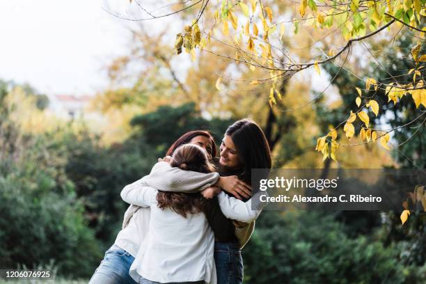 mother and daughters smiling and embracing by trees - alexandra mora bildbanksfoton och bilder