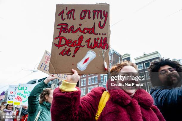 Woman is holding a placard with a sanitary towel with fake blood, during the Women's March held in Amsterdam, on March 8th, 2020.