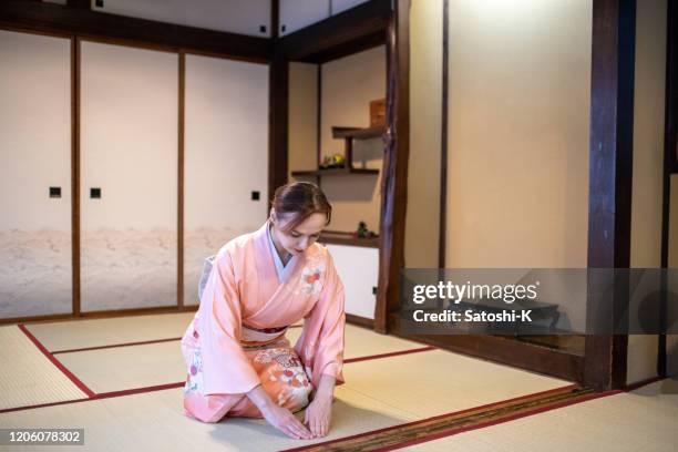 russische frau in kimono sitzen auf fersen und verbeugung in japanischen tatami zimmer - fersensitz stock-fotos und bilder