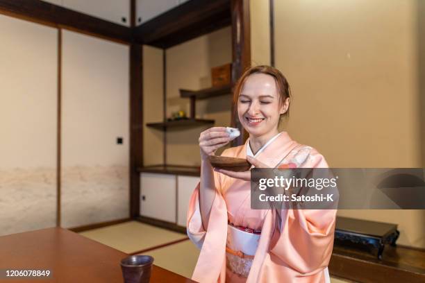 russische vrouw in kimono die met het eten van japanse wagashi snoepjes glimlacht - slavische-volkeren stockfoto's en -beelden