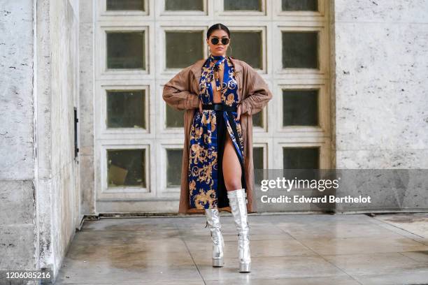 Guest wears Ray Ban sunglasses, earrings, a lustrous deep blue brocade opened kimono with a gold-tone pattern and a bow as necklace, a black belt, a...