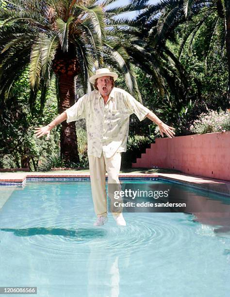 Monty Python legend Eric Idle 'walks on water' at his home pool in the Hollywood Hills, California in 1989. A plexiglass table was placed under the...