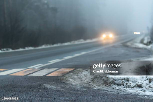 foggy country road in winter and blurred car in the distance - driving in fog stock pictures, royalty-free photos & images