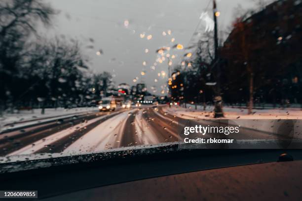 traffic stands still, on a cold, wet day, shot through a windscreen, focusing on the rain droplets, tailights out of focus - winter car window foto e immagini stock