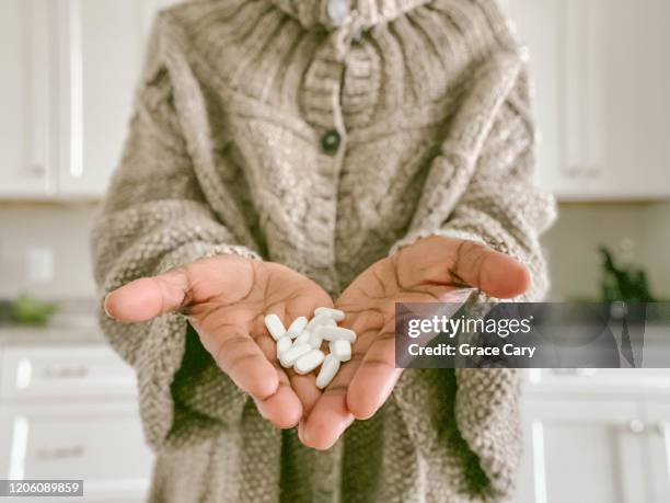 woman holds heap of pills in palm of hands - pijnstiller stockfoto's en -beelden