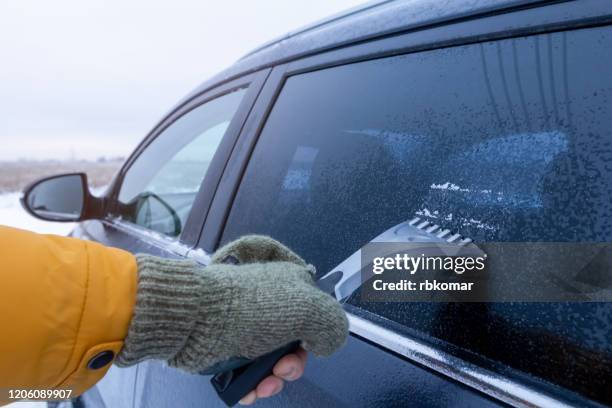 hand in glove scraper ice on car window - juckreiz stock-fotos und bilder