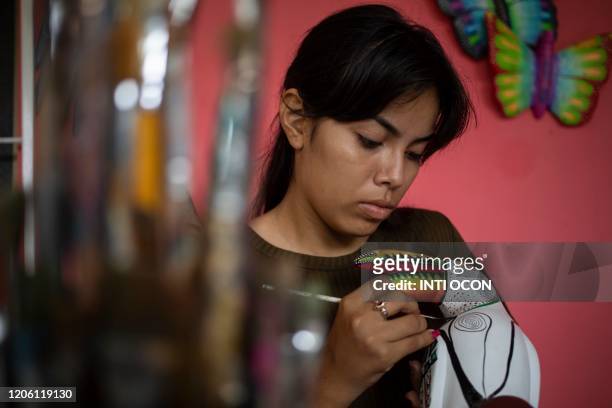 Craftswoman Olga Pena paints handicrafts to sell to tourists, in Mancarron Island, at the Solentiname archipielago, Nicaragua, on March 7, 2020. - In...