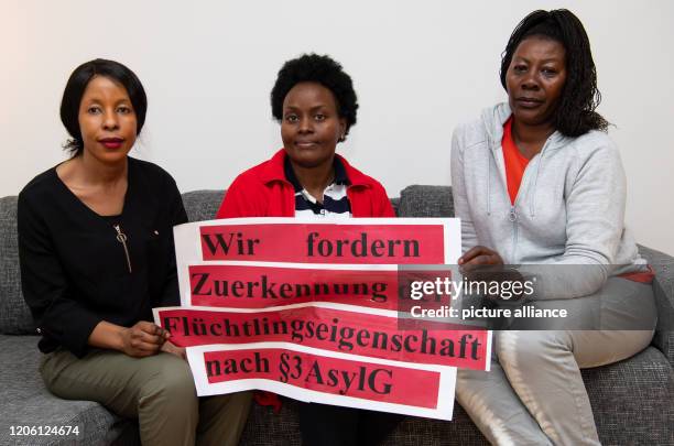 March 2020, Bavaria, Munich: Grace , Sandra and Racheal, lesbian women from Uganda, hold a poster with the words "We demand the granting of refugee...