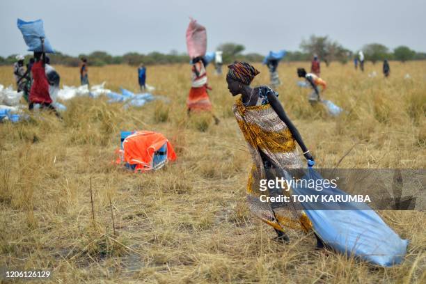Villagers collect food aid dropped from a plane in gunny bags from a plane onto a drop zone at a village in Ayod county, South Sudan, where World...