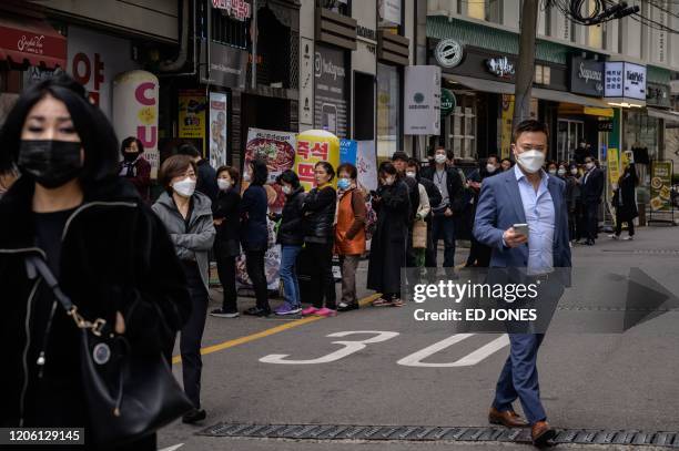 People queue to buy face masks amid concerns about the spread of the COVID-19 novel coronavirus, outside a pharmacy in Seoul on March 9, 2020. -...
