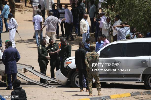 Security forces gather next to a damaged vehicle at the site of an assassination attempt against Sudan's Prime Minister Abdalla Hamdok, who survived...