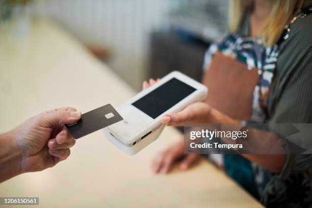 close up view of a hand holding a card near a card reader. - datafono stock pictures, royalty-free photos & images