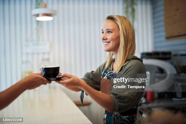 barista giving a cup of coffee to a costumer. - latte barista stock pictures, royalty-free photos & images