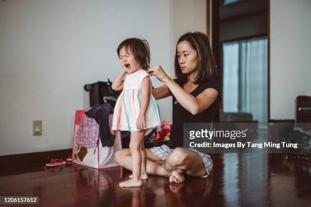 Mom dressing her just woke up daughter in the bedroom