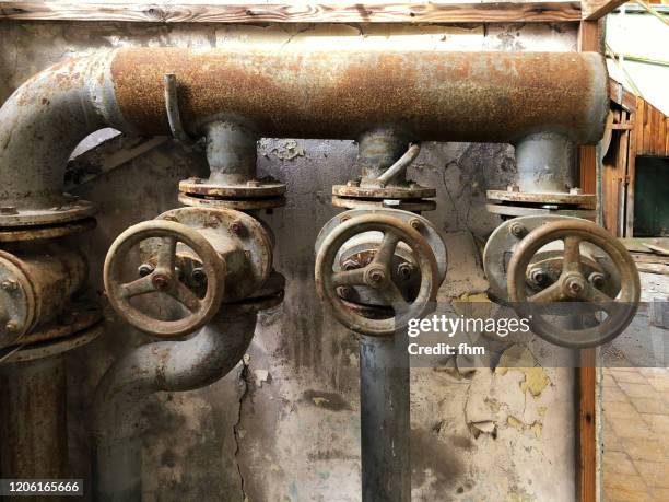 three valves and pipes in an abandoned building - rust germany photos et images de collection