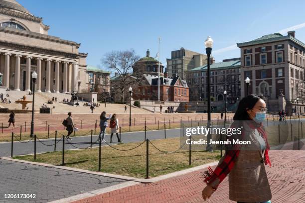 Woman wearing a protective mask walks on the Columbia University campus on March 9, 2020 in New York City. The university is canceling classes for...