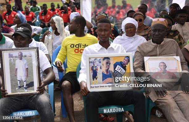 Relatives hold portraits of three of the nine members the Etoile de Guinee, the second-division team of a football club belonging to former...