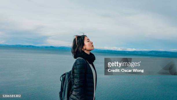 young woman at the mountain peak, seaview in the background - femme perou photos et images de collection
