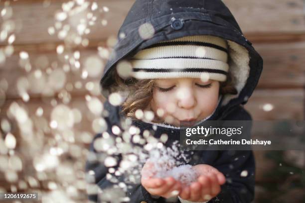 a 4 year old girl blowing on snowflakes - kid in winter coat stock pictures, royalty-free photos & images