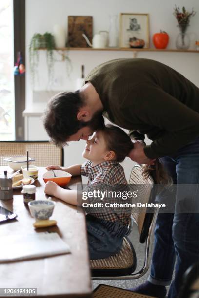 a father doing his daughter hair during the breakfast - hipster in a kitchen stock-fotos und bilder