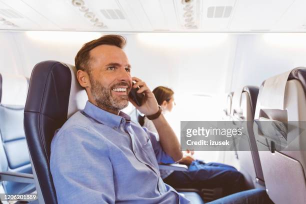 männlicher passagier spricht auf smartphone im flugzeug - male airport stock-fotos und bilder