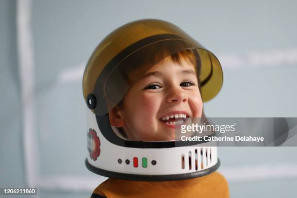 a four year old boy wearing a cosmonaut helmet, smiling at home - astronaut portrait stock-fotos und bilder