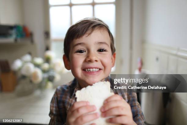 a four year old boy eating sliced bread in the kitchen - boy young cute stock-fotos und bilder