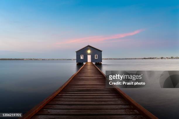 sunset over blue boathouse is a famous landmark with wooden bridge in the swan river in perth, western australia, australia. - perth australia foto e immagini stock
