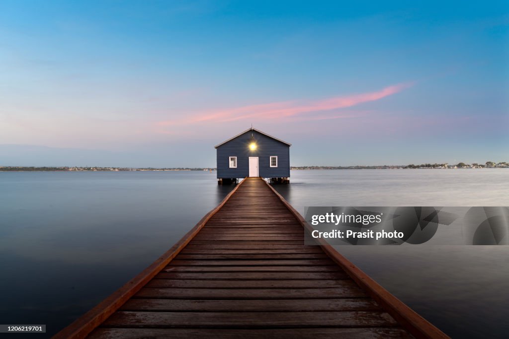 Sunset over blue boathouse is a famous landmark with wooden bridge in the Swan River in Perth, Western Australia, Australia.
