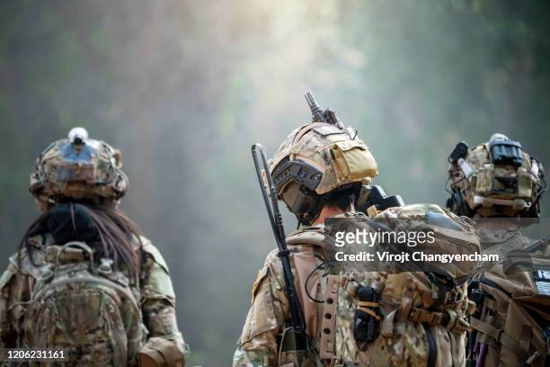 rear view of three soldiers patrolling along the risky area. - armed forces stock-fotos und bilder