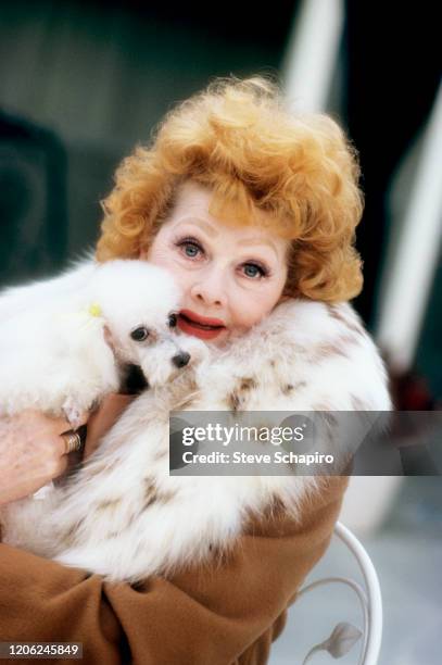 Portrait of American actress and comedienne Lucille Ball as she poses with a dog in her arms, Los Angeles, California, 1980.