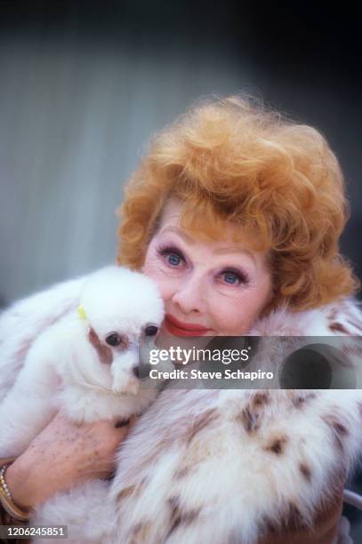 Portrait of American actress and comedienne Lucille Ball as she poses with a dog in her arms, Los Angeles, California, 1980.