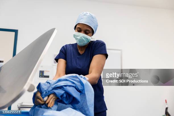 mature female surgeon taking off surgical gown - hospital gown imagens e fotografias de stock