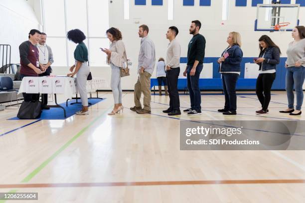 gruppe von menschen wartet in langer schlange im wahllokal - poll vote stock-fotos und bilder