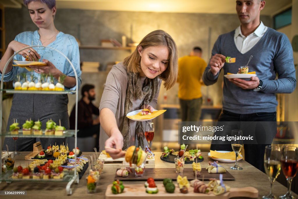 Schöne junge Frau, die Essen während der Arbeit Abendessen Party