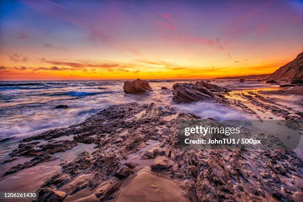 sunset over muddy coastline with rocks, crystal cove, newport beach, california, usa - newport beach california stock-fotos und bilder