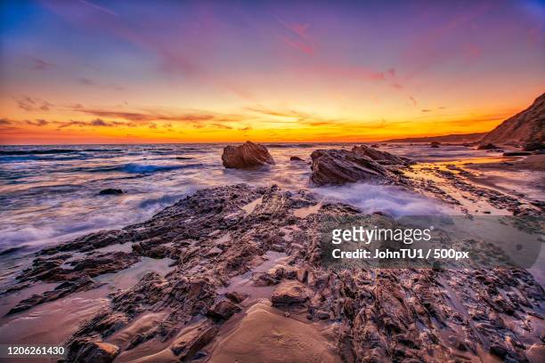 sunset over muddy coastline with rocks, crystal cove, newport beach, california, usa - newport beach california fotografías e imágenes de stock