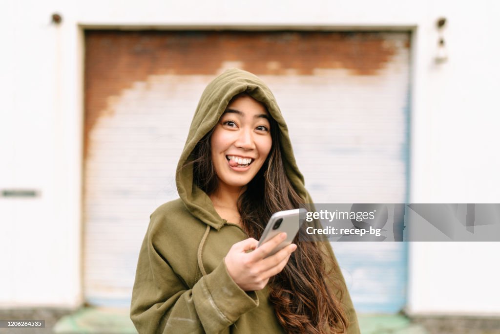 Portret van jonge vrouw die slimme telefoon houdt en grappig gezicht maakt