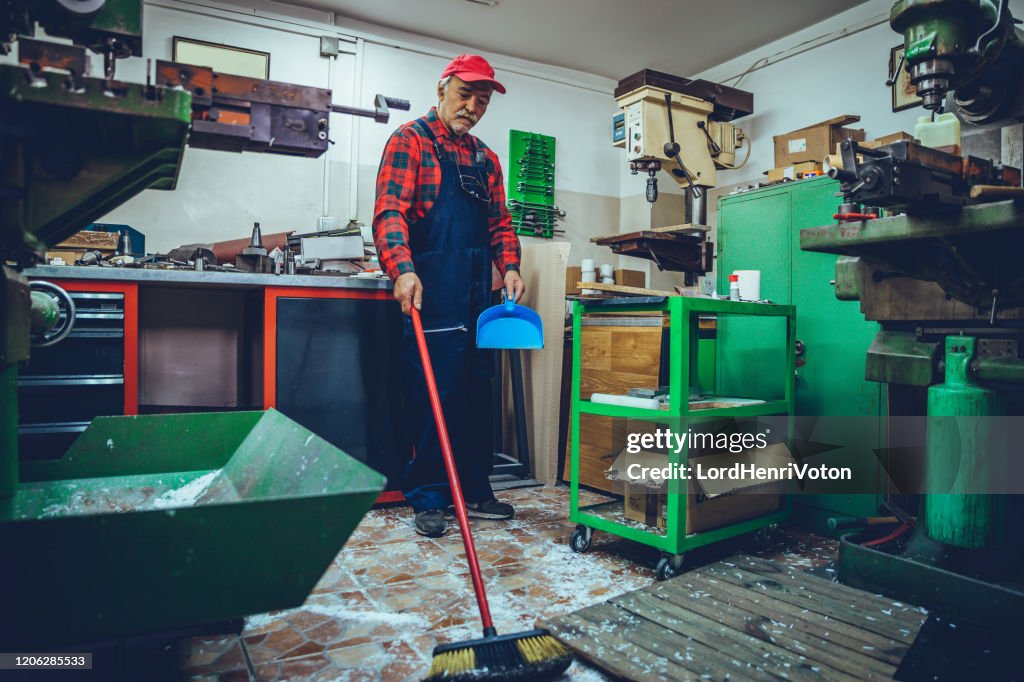 Senior craftsman using broom