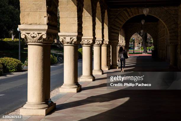 Person walks past archways during a quiet morning at Stanford University on March 9, 2020 in Stanford, California. Stanford University announced that...