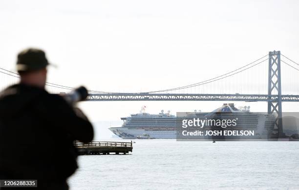 Photographer watches as the Grand Princess cruise ship passes under the Bay Bridge towards Oakland, Californi on March 9, 2020 - A cruise ship...